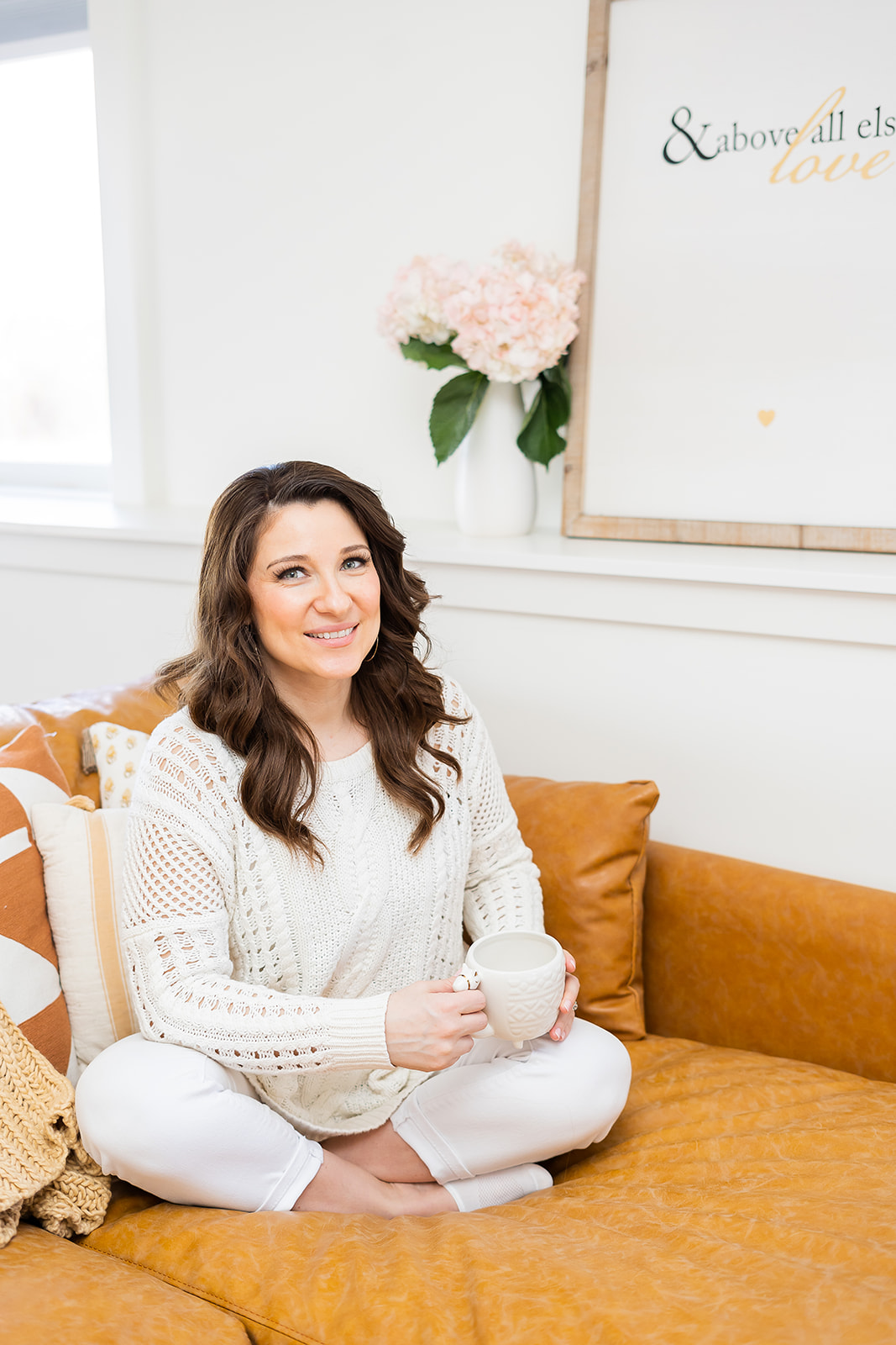 A business owner sitting on a couch with a mug during a light and airy branding photography session in Rockville, Maryland. 