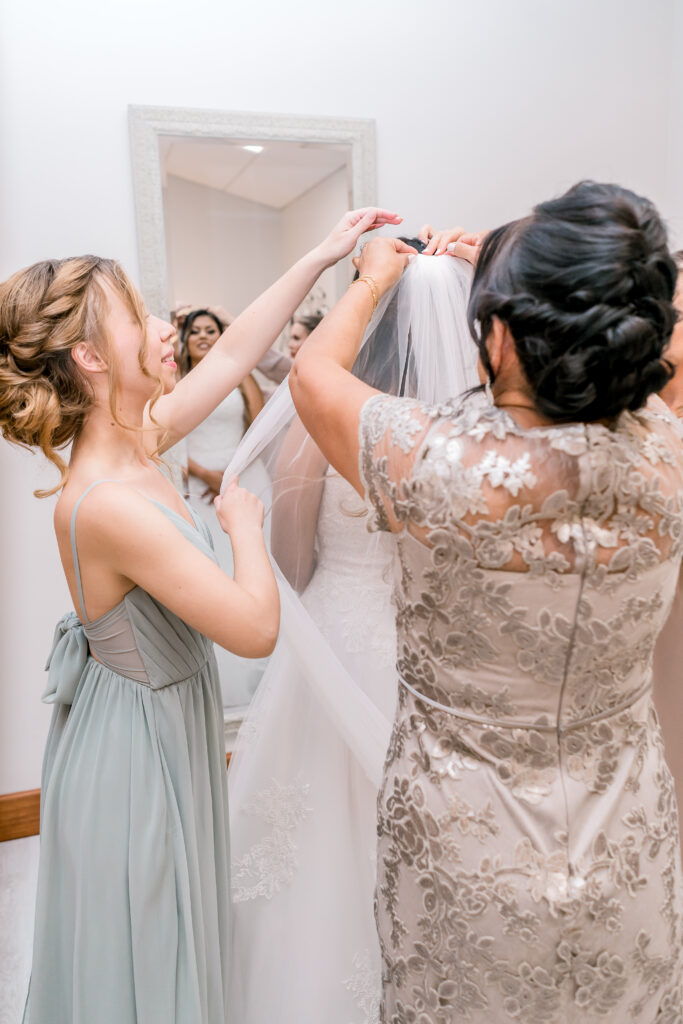 Bridesmaids and stepmother helping the bride to get dressed.